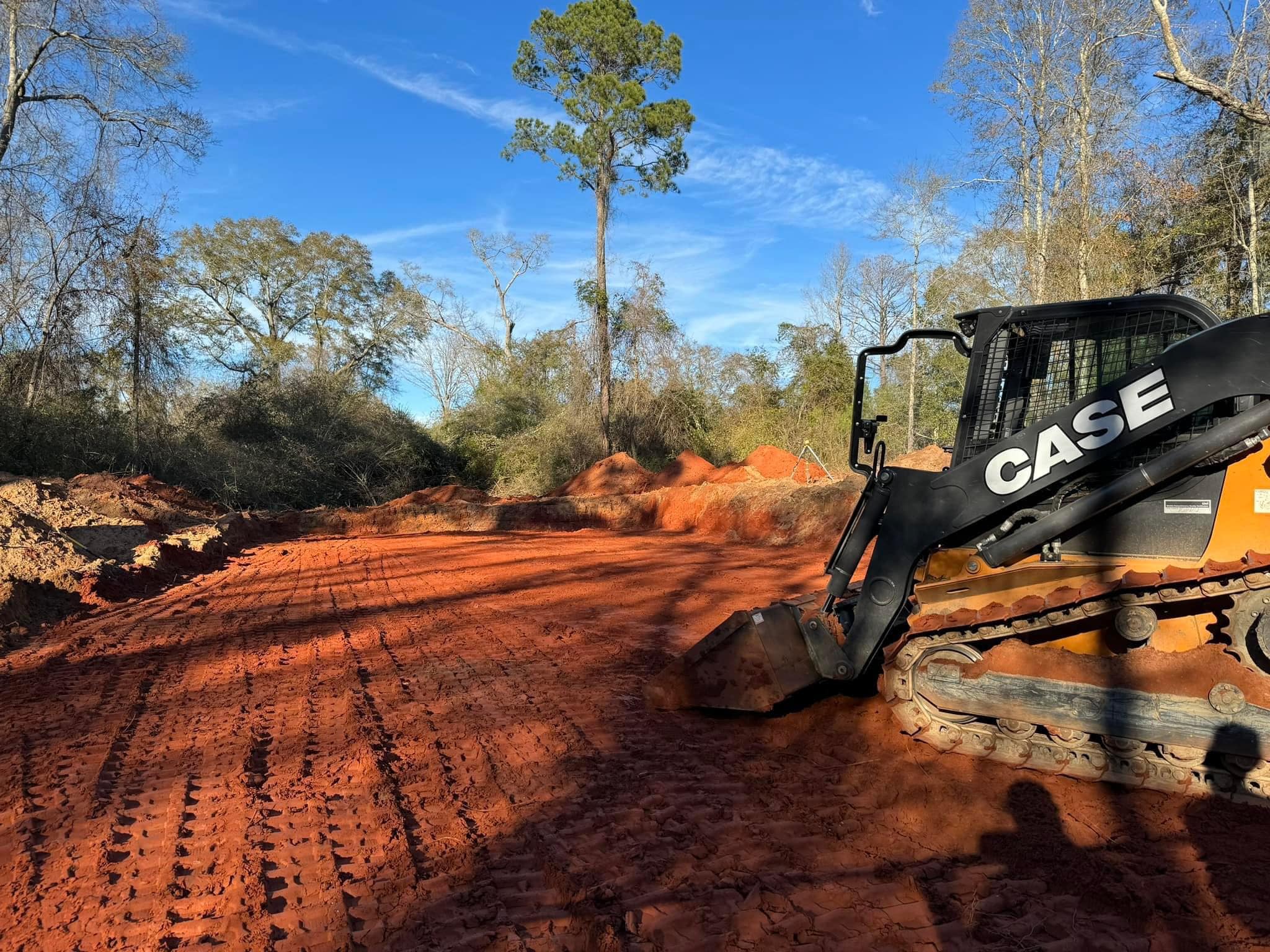Track loader performing dirt work with red clay