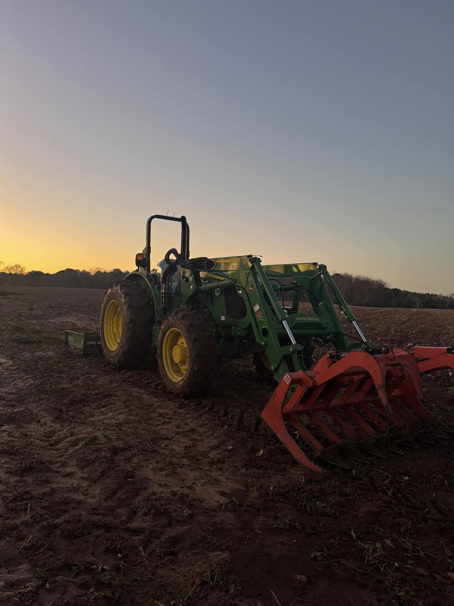 John Deere tractor with front loader in cleared field