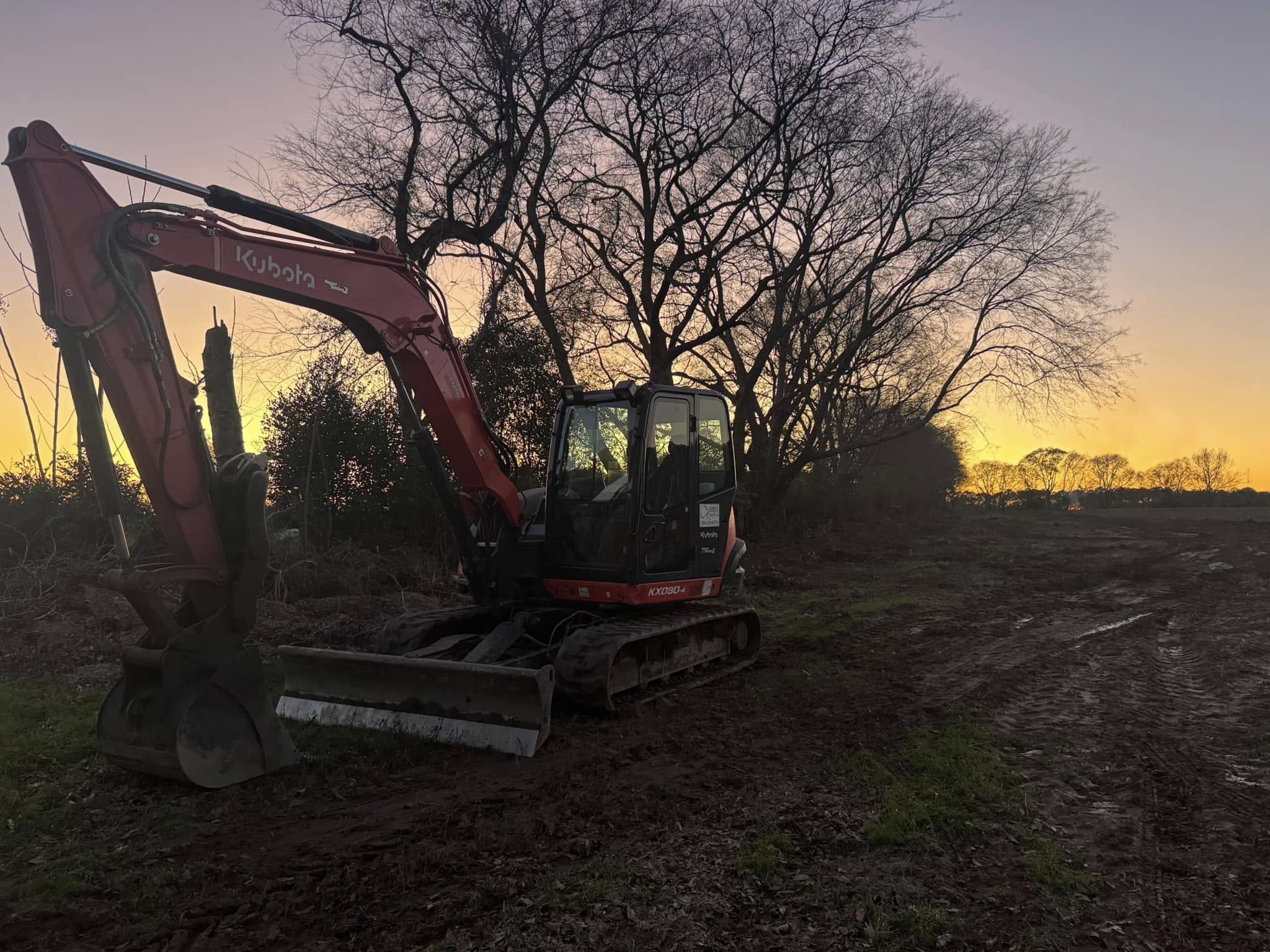 Kubota excavator at sunset in cleared area