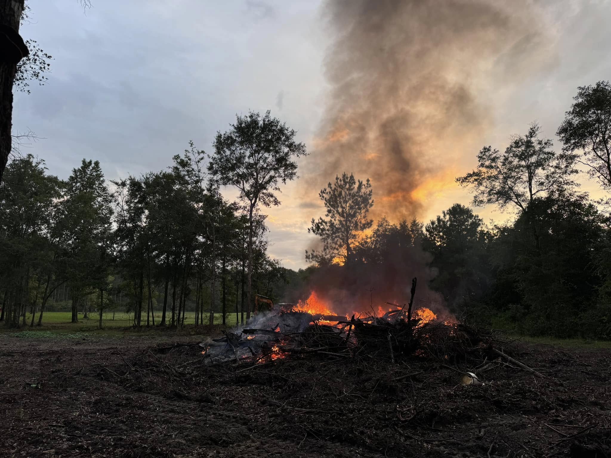 Large burn pile with flames at sunset